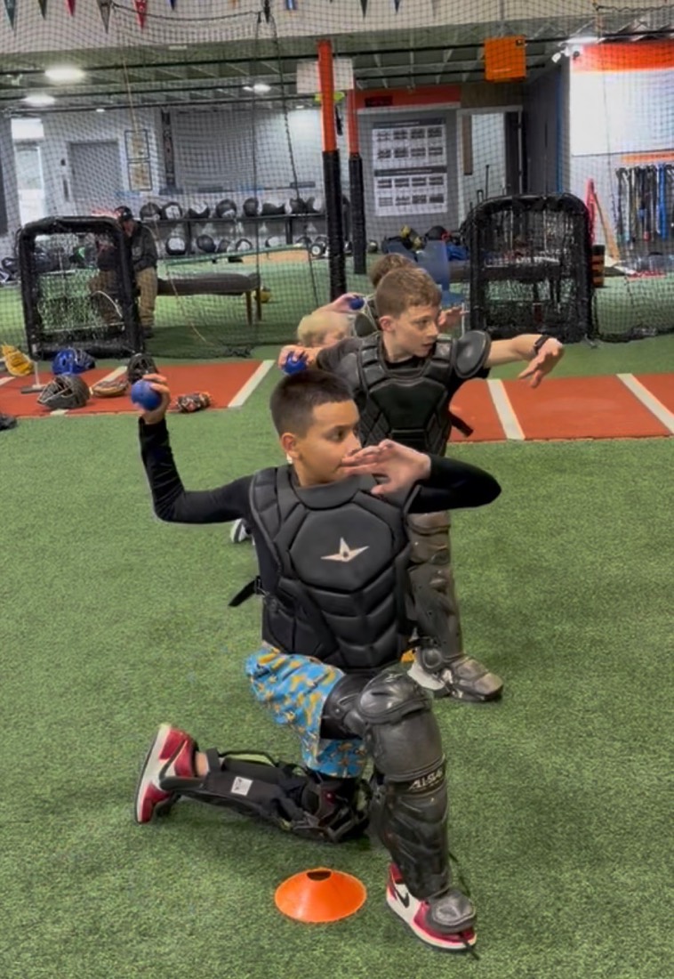 Coach Juan leading a catching drill with young players